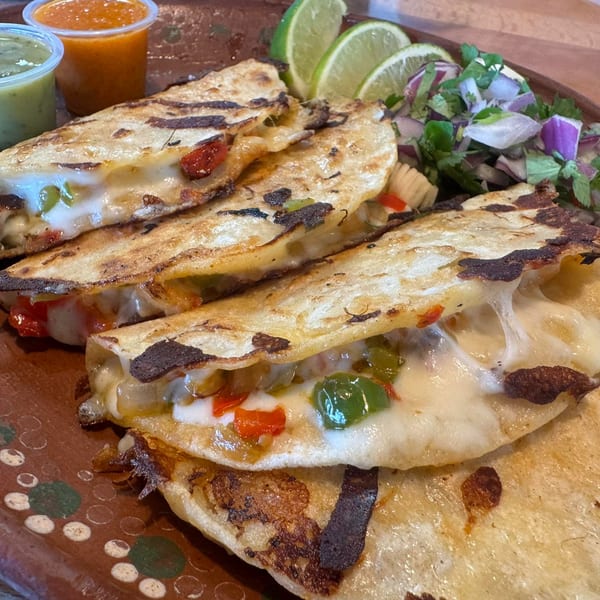 Cheesy quesadillas with green and red peppers, served with salsa, limes, and a side salad.